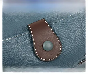 Détail du cuir grainé bleu avec sangle marron et surpiqûres blanches contrastées