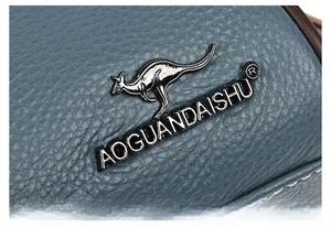 Détail de la texture en cuir bleu grainé et du logo métallique de la marque kangourou
