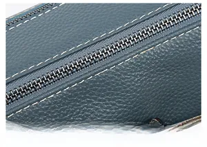 Détail de la fermeture éclair et de la texture cuir grainé bleu du sac à bandoulière