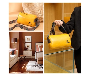 Detail of yellow cylinder bag featuring a black kangaroo logo and woven colorful strap