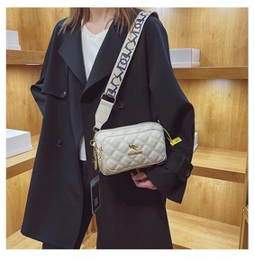 Detail of white quilted crossbody bag with golden kangaroo logo and stylish wide strap