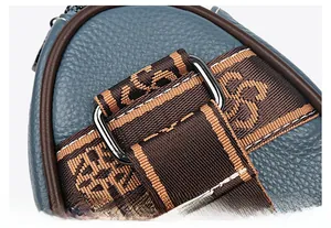 Détail de boucle argentée polie et sangle jacquard sur sac en cuir bleu grainé