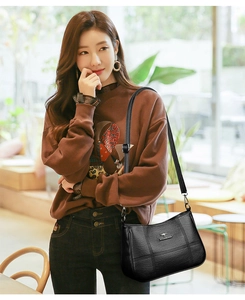 Detail of premium black leather shoulder bag with kangaroo metal logo and fine stitching