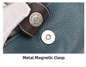 Gros plan sur la boucle magnétique argentée et le cuir bleu grainé d'un sac bandoulière
