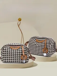 Detail of elegant houndstooth crossbody bag with leather trim and gold zipper pendant