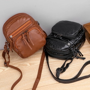Brown and black soft PU leather crossbody bags with multi-zipper pockets on wood table