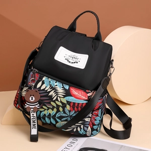 Black women's backpack with colorful leaf print, detachable strap, and plush charm