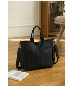 Détail du sac fourre-tout noir en toile avec poches latérales et bandoulière réglable