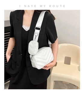 Detail einer weißen Stepptasche mit kleinem Beutel und breitem Schultergurt