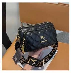 Detail of black quilted crossbody bag featuring gold kangaroo logo and wide fabric strap