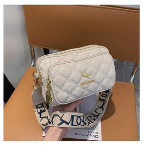Detail of cream quilted leather bag with golden kangaroo logo and patterned strap