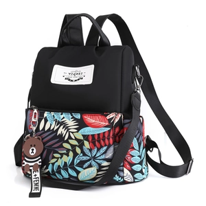 Black waterproof backpack with vibrant leaf print and cute bear pendant accessory