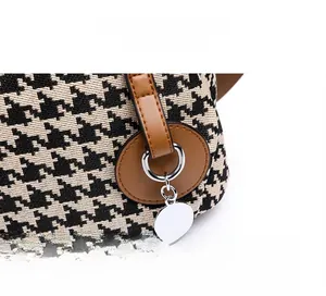 Detail of houndstooth fabric with brown faux leather trim and silver metal charm
