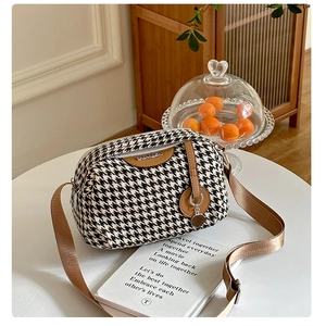 Detail shot of houndstooth canvas crossbody bag with brown leather trim and metal logo