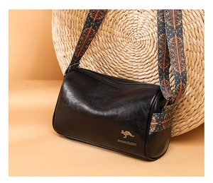 Detail of black cylindrical bag with glossy PU leather and bohemian patterned strap