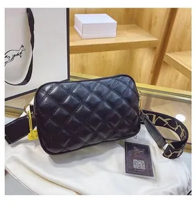 Detail of black quilted camera bag with glossy finish and wide jacquard shoulder strap