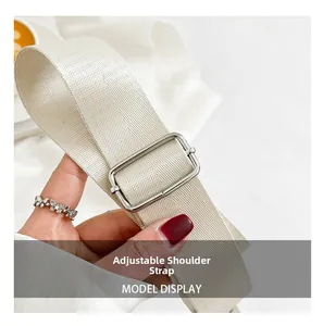 Detail of adjustable off-white woven shoulder strap with silver metal buckle on handbag