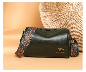 Detail of dark green cylindrical bag showing glossy leather and ethnic pattern strap