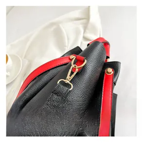 Close-up of premium gold hardware on black lychee leather handbag with red strap