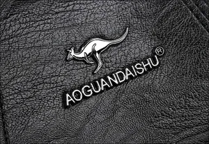 Makroaufnahme der schwarzen Leder-Litschistruktur mit silbernem Metall-Känguru-Logo