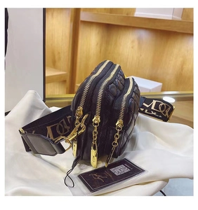 Macro view of black quilted crossbody bag showing triple zipper layers and gold hardware
