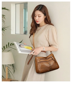 Detail showing multi-pocket brown retro leather crossbody bag with metal rivets and zippers