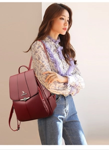 Detail of burgundy PU leather backpack with gold kangaroo logo and lychee grain texture