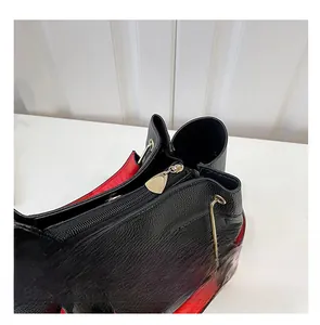 Detail of smooth golden zipper and black pebble leather bag with red lining
