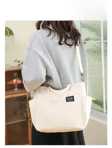 Vue arrière détaillée d'un sac cabas en toile crème porté par un mannequin en intérieur