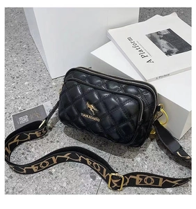 Detail of black quilted leather crossbody bag with dual zippers and wide patterned strap