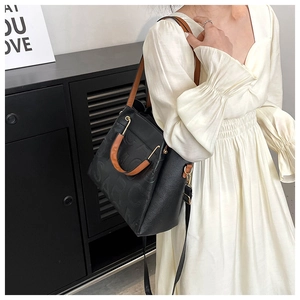 Detail of black lychee grain leather handbag with embossed letters and brown handles