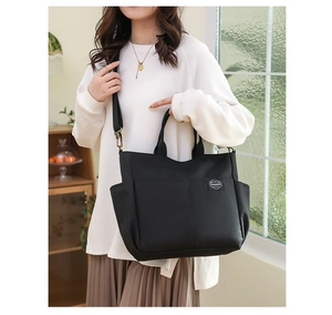 Détail d'un sac cabas en toile noire avec patch tissé et bandoulière réglable