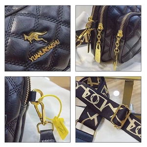 Macro shot of quilted black leather texture with gold kangaroo logo and zipper detail