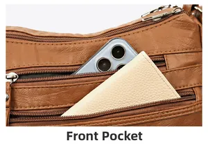 Detailed view of the front zipper pocket on a brown leather crossbody bag with items inside