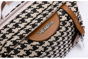 Detailed close-up of houndstooth fabric texture and brown leather trim with silver logo