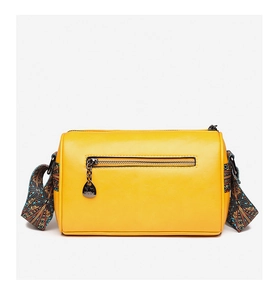 Macro shot of yellow cylinder crossbody bag with cat charm and ethnic jacquard strap