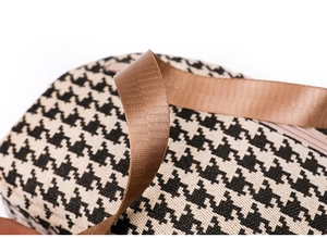 Detail of classic black and white houndstooth canvas bag with brown nylon strap detail