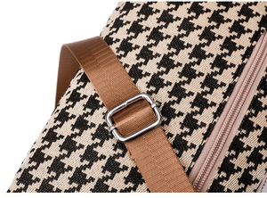 Detail of houndstooth canvas bag featuring brown nylon strap and silver metal buckle