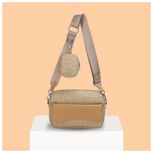 Detail view of woven crossbody bag with round coin purse and wide canvas strap on white stand