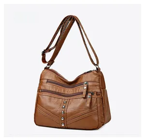 Macro side view of brown PU leather crossbody bag with multiple zippers and metal rivets