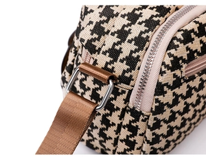 Close-up of houndstooth weave fabric with silver metal D-ring and brown strap details
