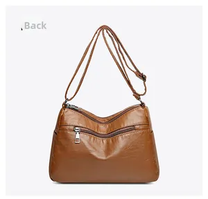 Detailed back view of a brown soft leather crossbody bag with three zipper compartments