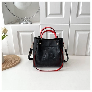 Detail of black pebbled leather tote with red handles and embossed letter patterns