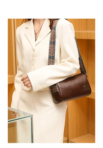 Detail of dark brown leather cylinder bag with ethnic patterned wide strap on a model
