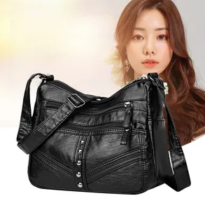 Detail of soft black leather hobo bag with triple front zippers and silver rivet accents