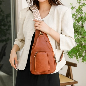 Detail of brown litchi leather sling bag with geometric pattern wide strap and metal zip