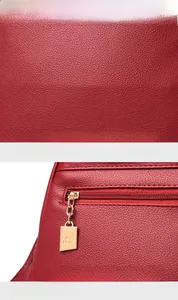 Detail of red pebbled leather texture and gold-tone kangaroo logo metal zipper puller