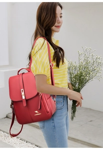 Detail of red leather backpack with gold kangaroo logo and secure metal buckle