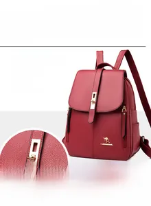 Detail of elegant gold metal kangaroo logo and sturdy clasp on dark red leather backpack
