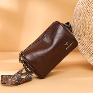 Brown soft PU leather crossbody bag with wide ethnic pattern strap on orange background
